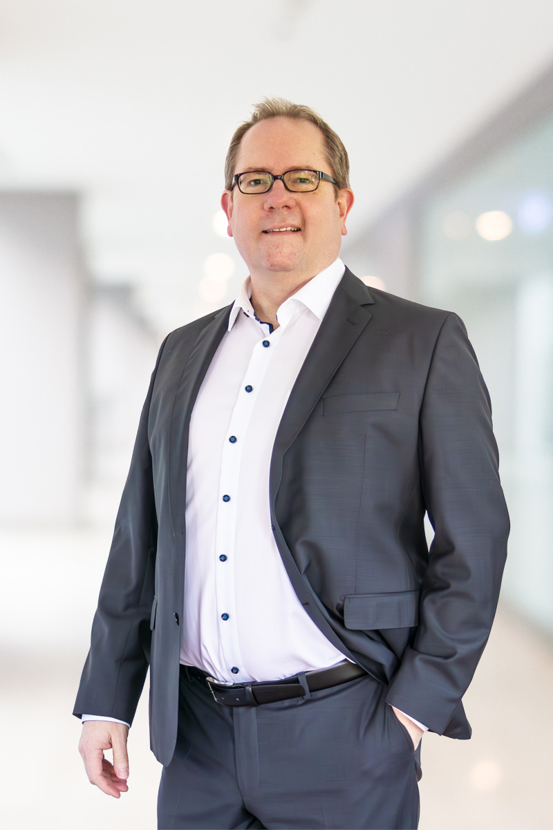 Dr. Marcus Schneider: Ein professionelles, aber nahbares Foto. Kein steifer Anzug, eher Hemd/hochgekrempelte Ärmel oder dezentes T-Shirt unter Sakko. Blickkontakt. Er strahlt „Macher-Kompetenz“ aus.